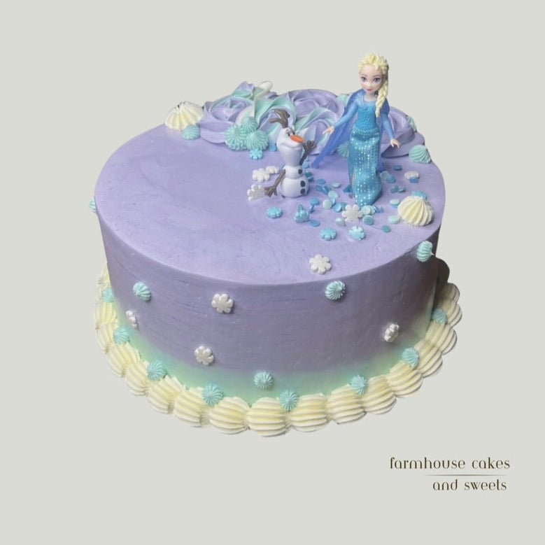 Icy princess themed cake with lavender and sky blue ombre color buttercream, snowflake decorations, and white piping details.
