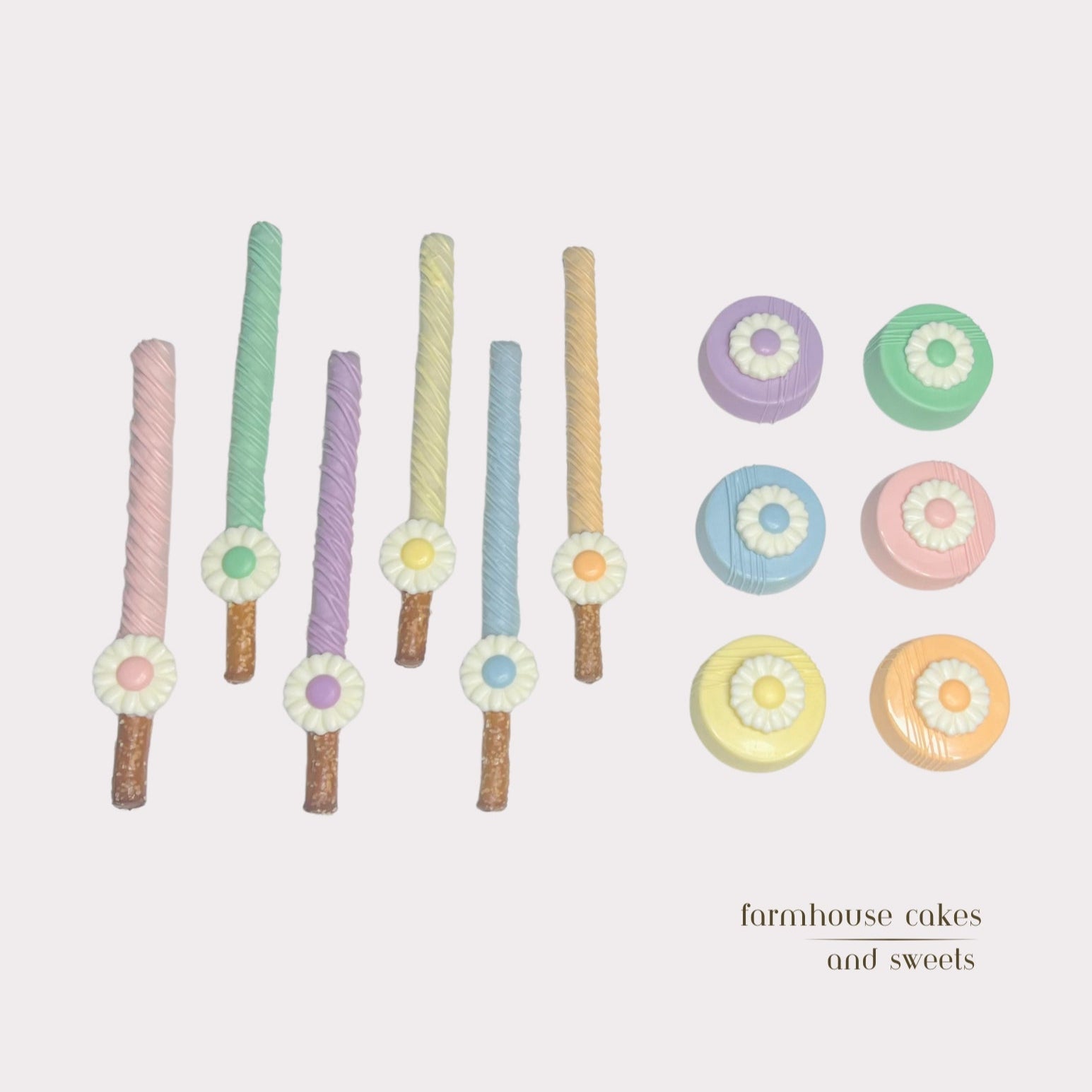 Assorted pastel chocolate-covered Oreos and pretzel rods topped with white chocolate daisies, perfect for spring gifts, baby showers, and party favors handcrafted by Farmhouse Cakes and Sweets.