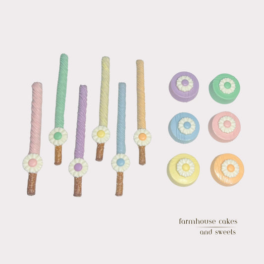 Assorted pastel chocolate-covered Oreos and pretzel rods topped with white chocolate daisies, perfect for spring gifts, baby showers, and party favors handcrafted by Farmhouse Cakes and Sweets.